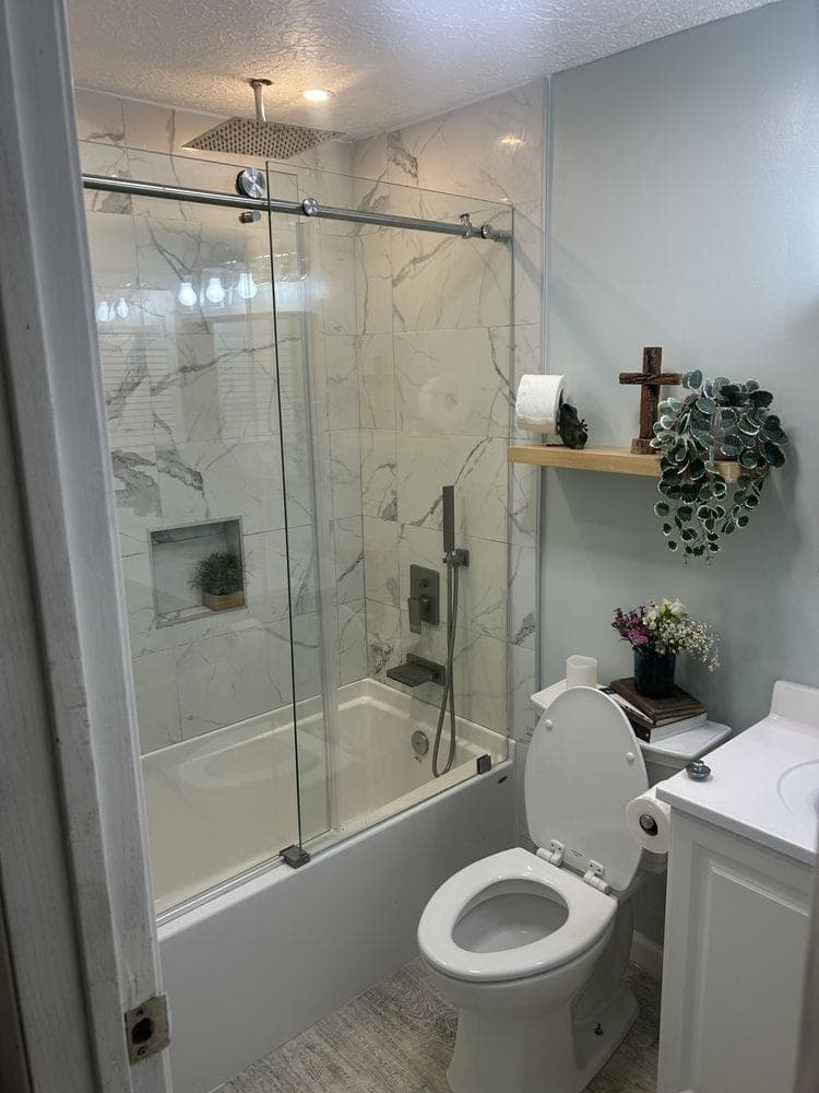 Finished bathroom remodel in Dublin, OH with marble-look tile, a sliding glass shower door and a white vanity