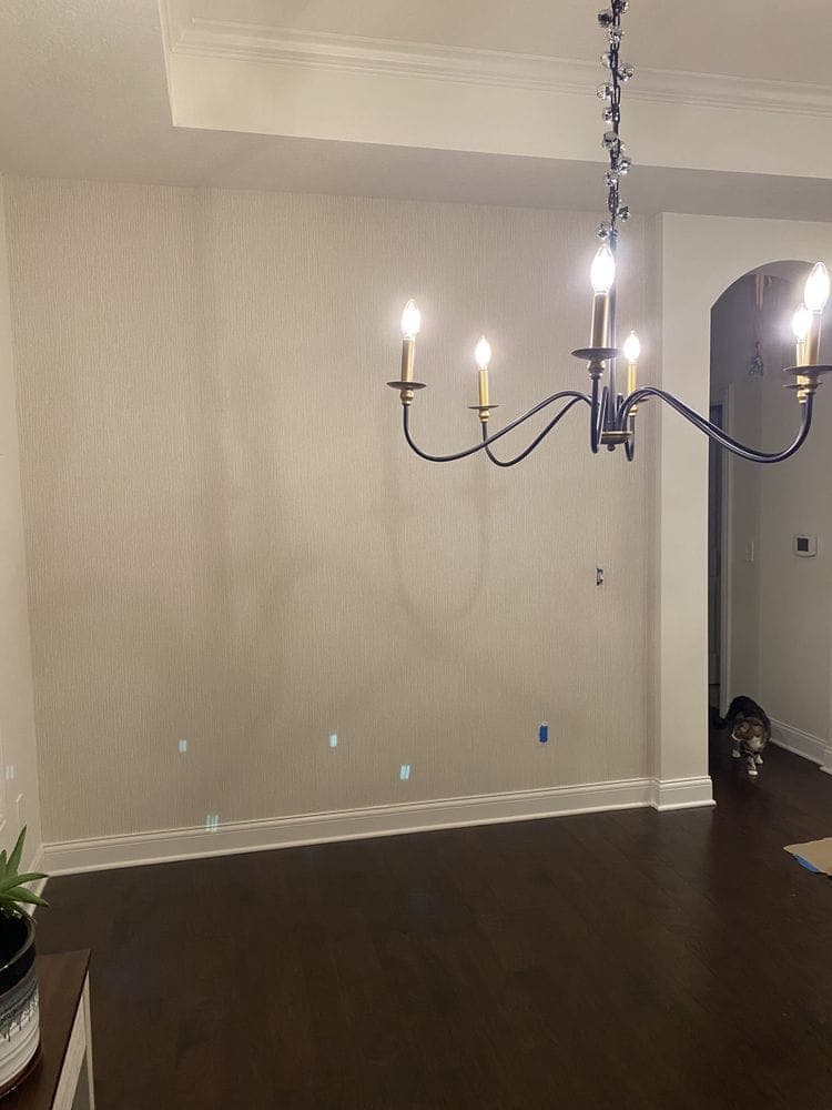 Finished interior room with fresh walls, dark wood floors and a new chandelier
