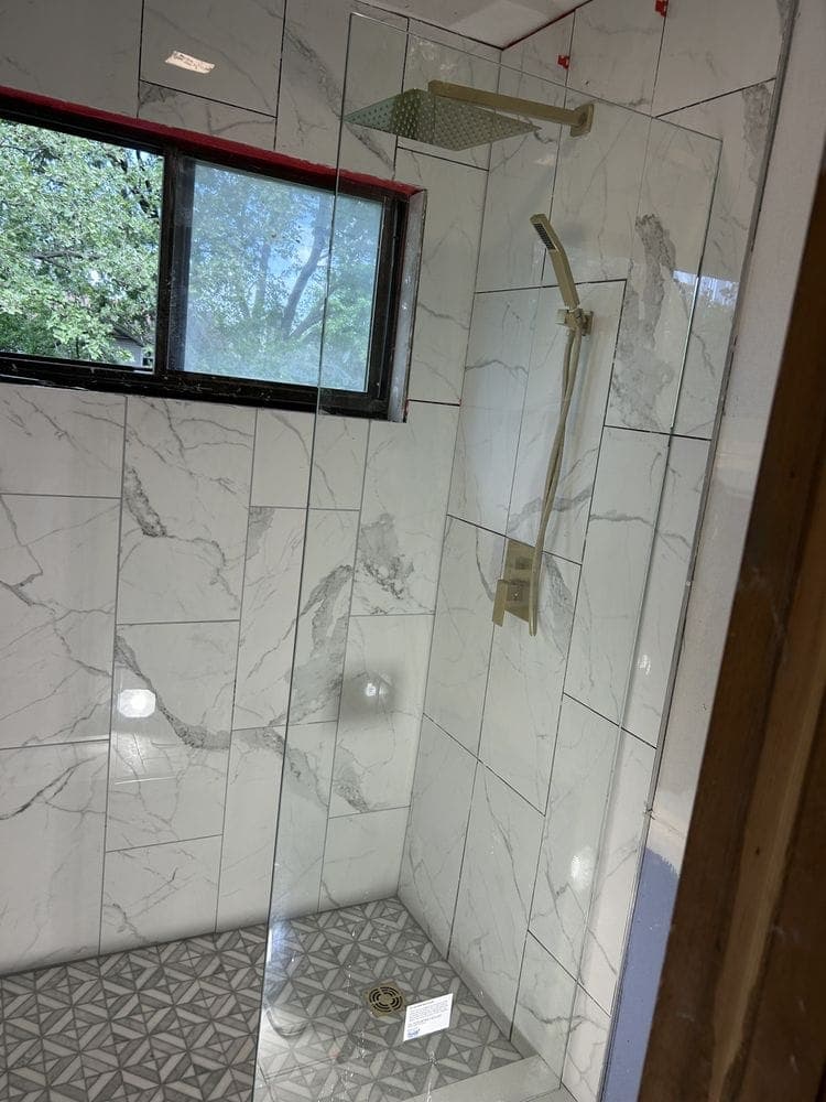 Walk-in shower with marble-look tile and brushed gold fixtures